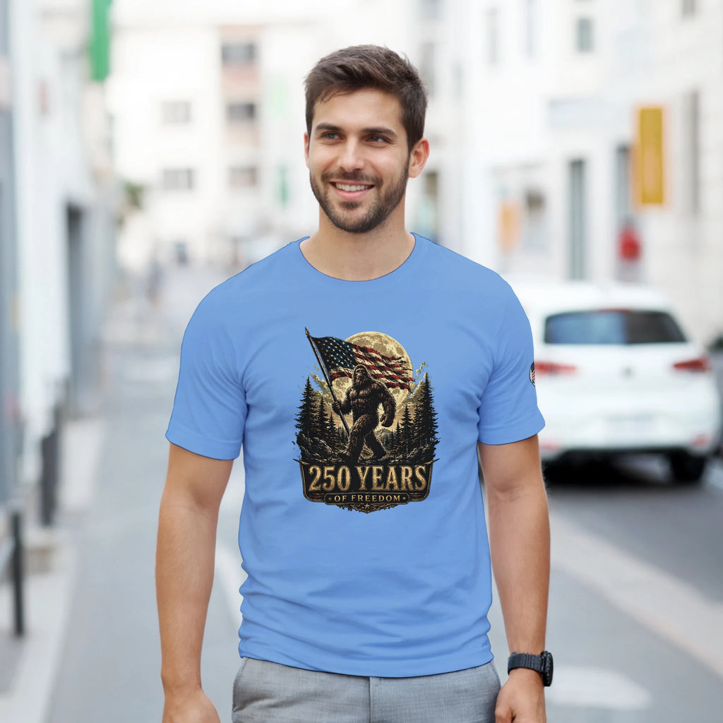 Man wearing a blue t-shirt with a Bigfoot graphic design on a city street