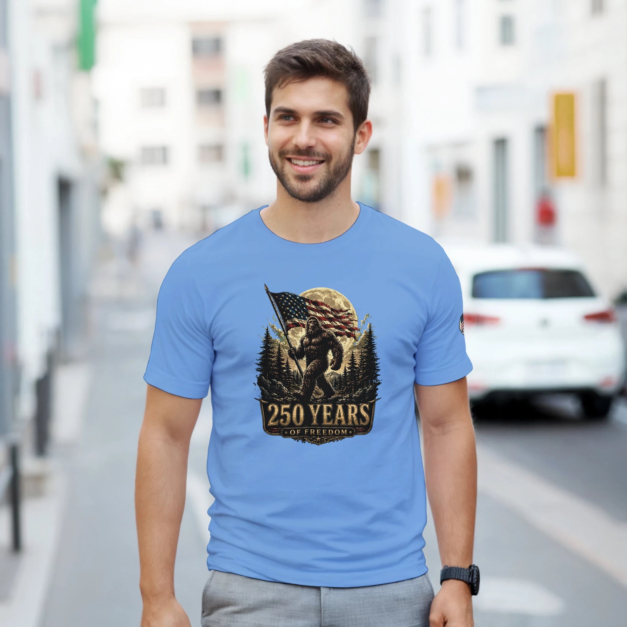 Man wearing a blue t-shirt with a Bigfoot graphic design on a city street