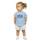 Child wearing a light blue t-shirt with 'USA' text and white shorts on a white background