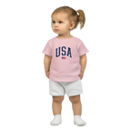 Child wearing a pink t-shirt with 'USA' and white shorts on a white background