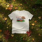 White t-shirt from the Love Collection with a graphic design of a camper van and trees on a grassy background with fallen leaves.